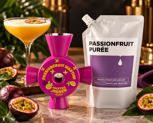Passionfruit Martini Cocktail Jigger beside a 500ml pouch of Bristol Syrup Co passionfruit purée and a passionfruit martini garnished with half a passionfruit, surrounded by fresh passionfruit